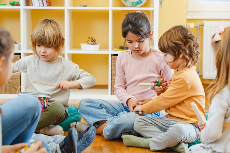 Tre børnehavebørn spiller på instrumenter